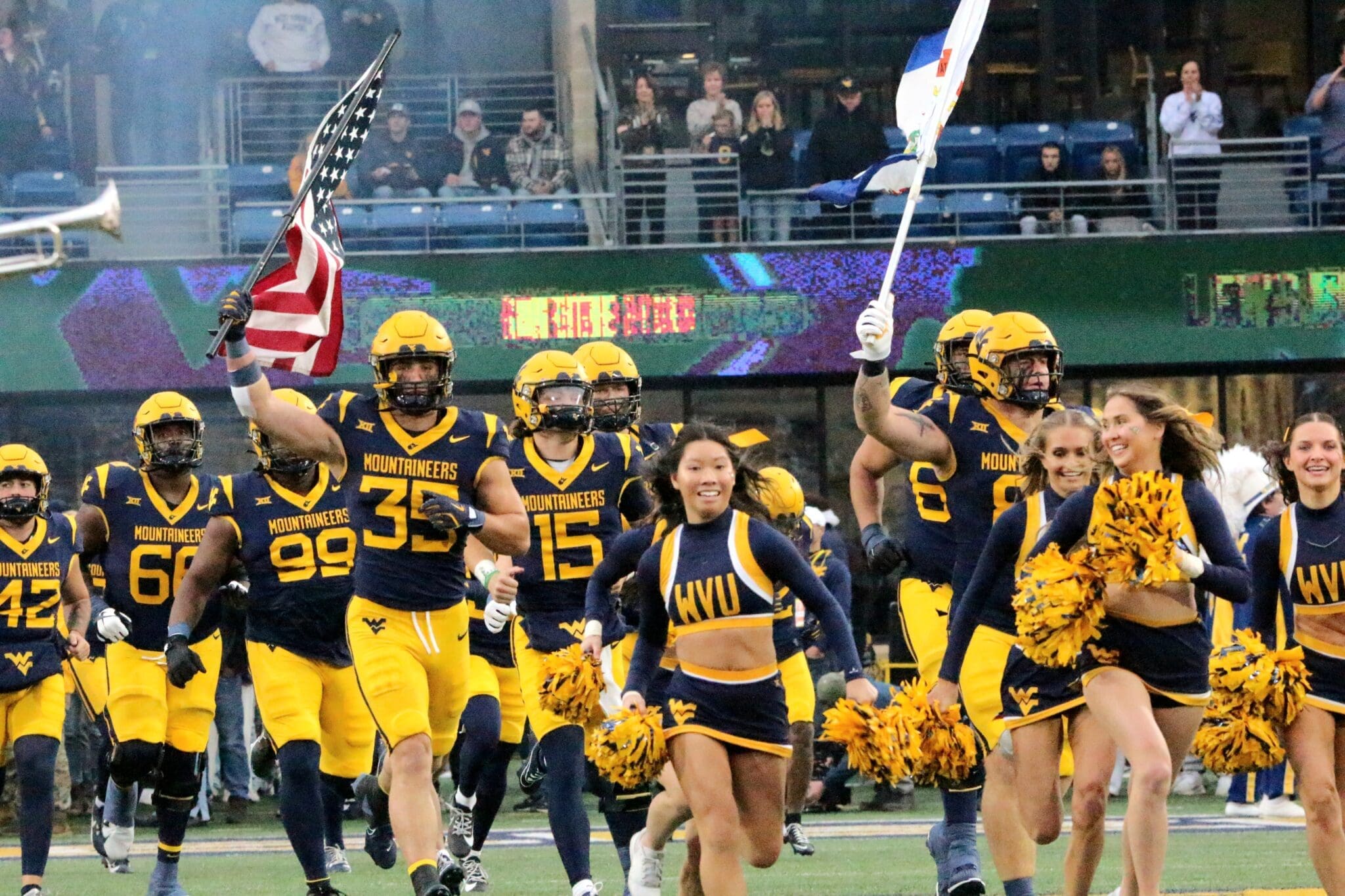 WVU Football team led Reid Carrico with US and WV flag and cheerleaders
