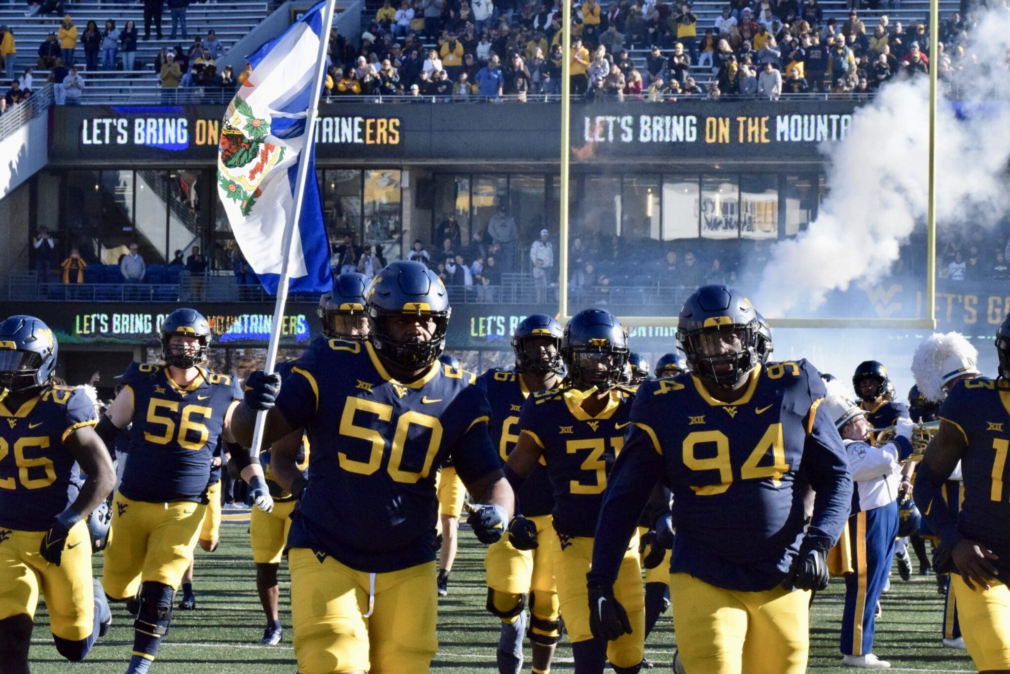 WVU Football team carrying flag