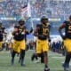 WVU Football players run on field with flag, including OL Wyatt Milum