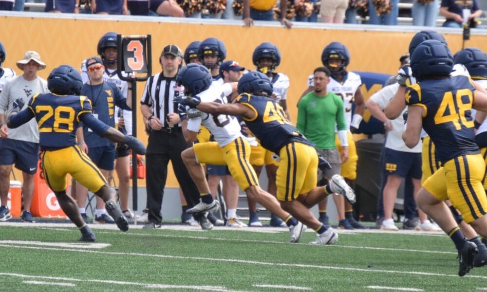 WVU Football players making a tackle during scrimmage with Troy Fischer in corner