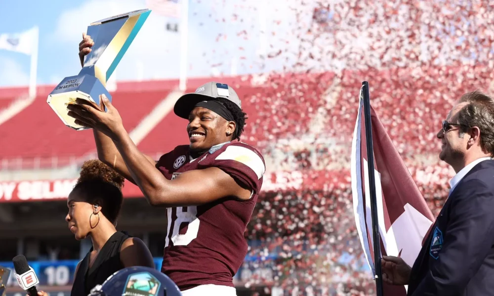 WVU Football WR Justin Robinson holding trophy with Mississippi State