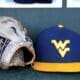 A WVU baseball hat and glove sits in the dugout as the Mountaineers played against North Carolina on June 8, 2024, in the Super Regionals of the NCAA Tournament at Boshamer Stadium in Chapel Hill, N.C. (Mitchell Northam / WV Sports Now)