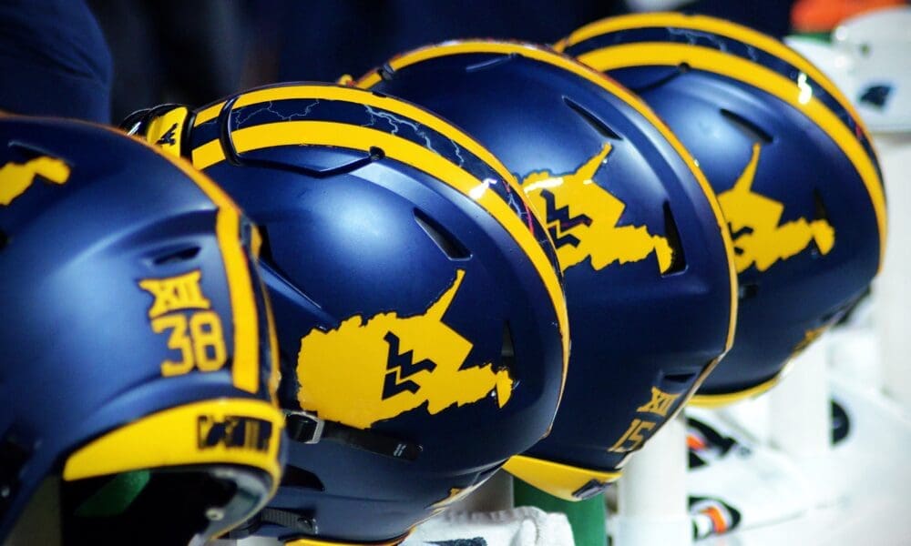 WVU Football helmets rest on the sideline stock